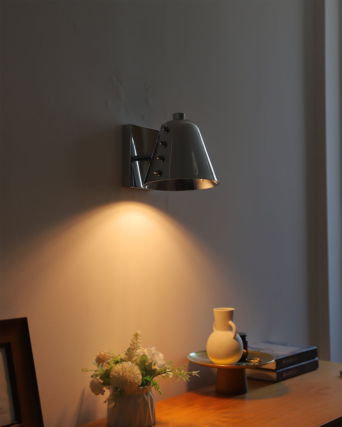Bespoke wall lamp in chrome, reflecting light.