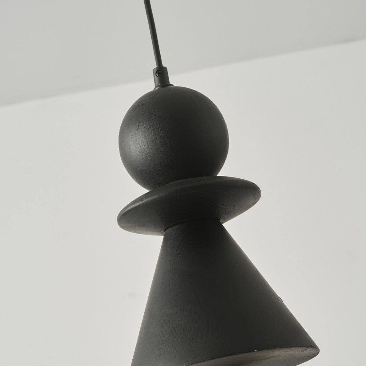 The black version of the Bodie pendant light against a light wall.