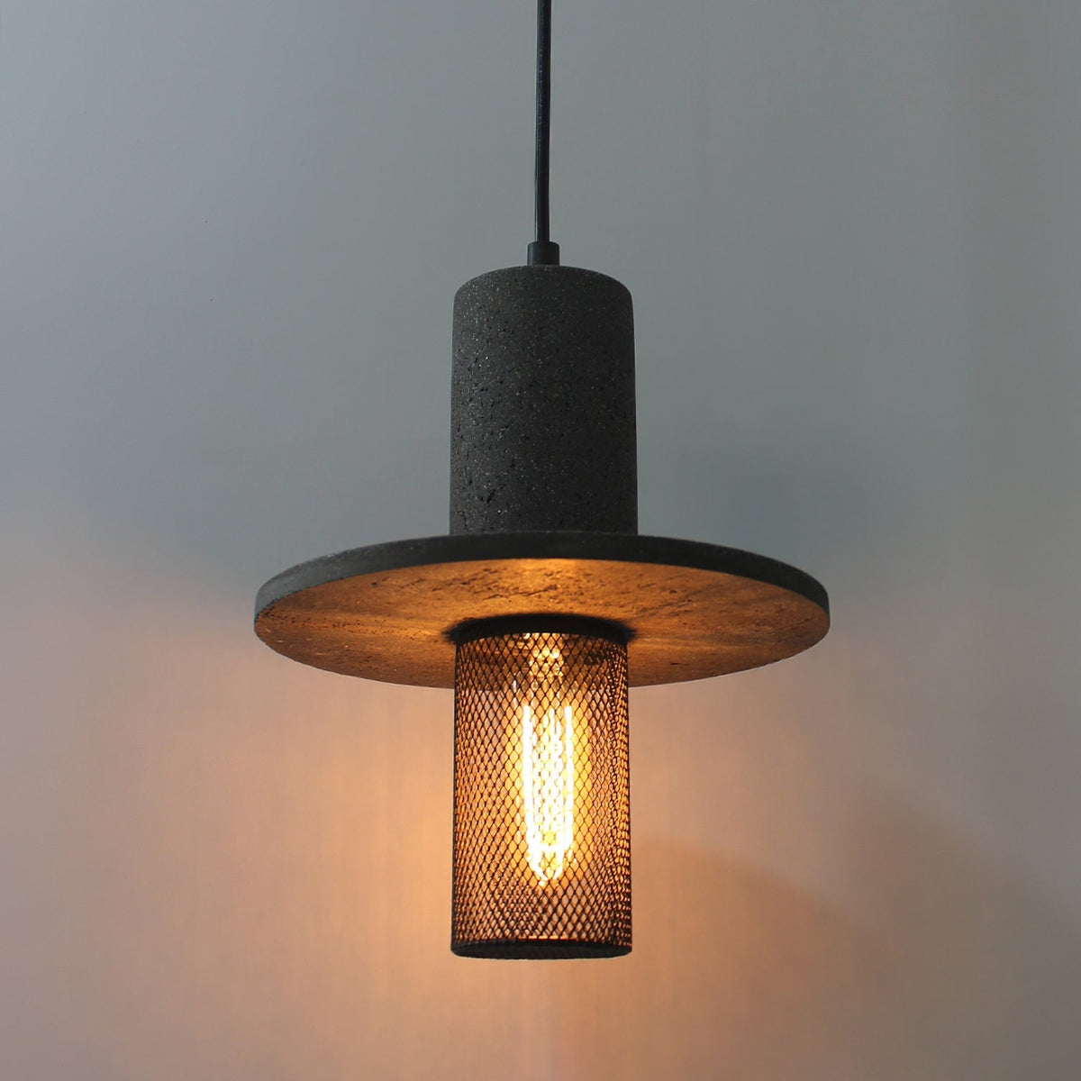 Close-up view of the Condo Pendant Light's travertine body and mesh diffuser.