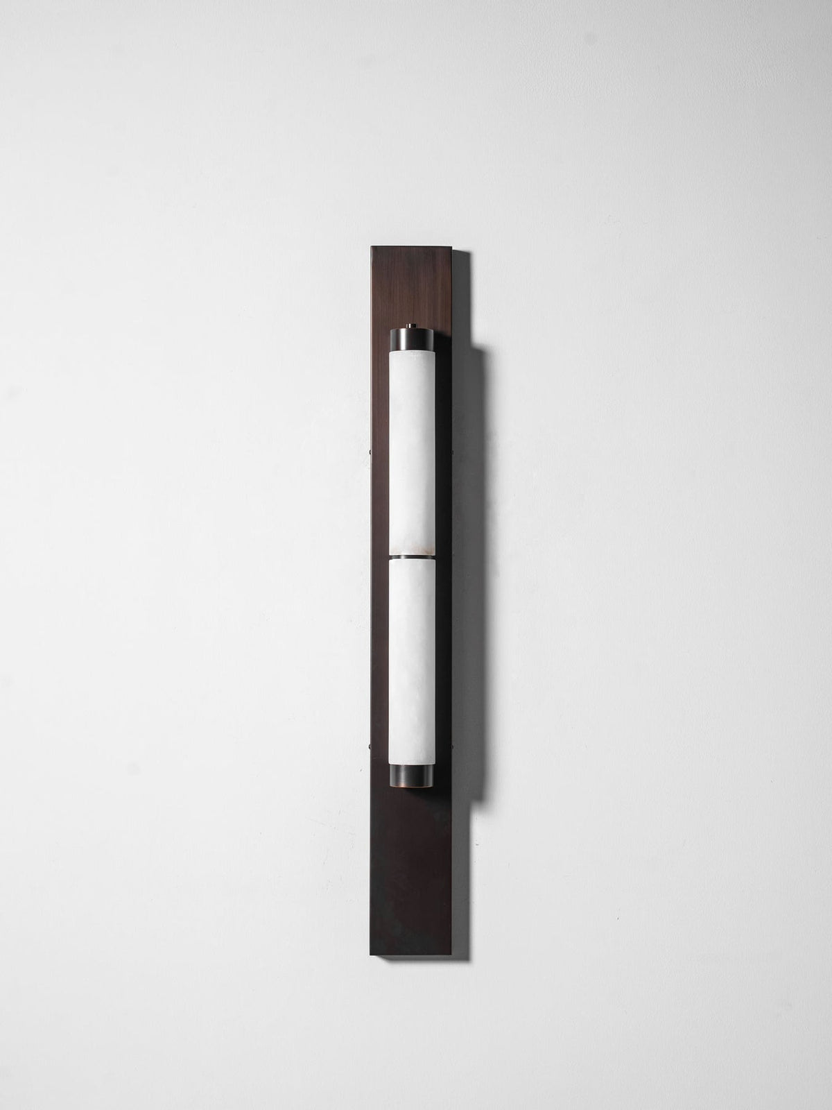 The brass backplate of the Columnar Alabaster Wall Lamp.
