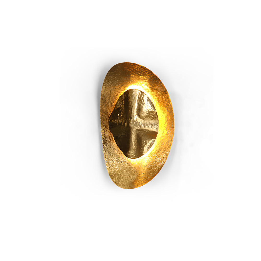 Helios Hammered Brass Sconce installed in a modern living room.