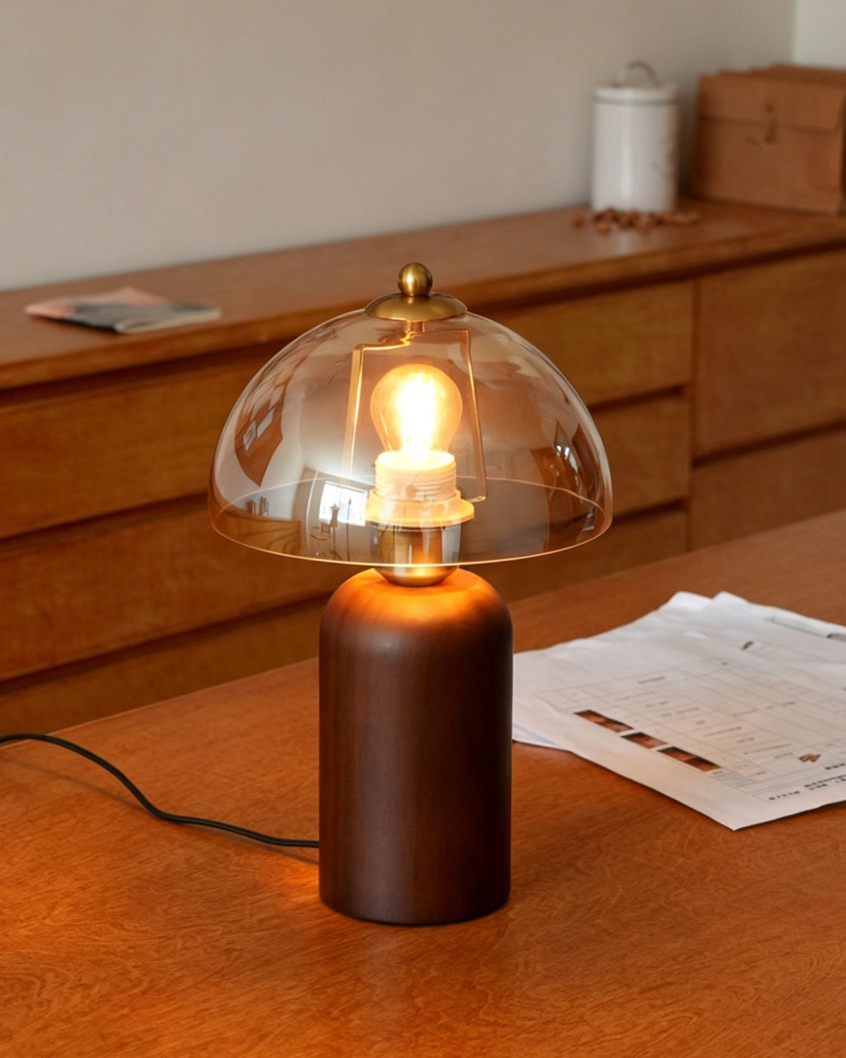 Close-up of the Disko Table Lamp's amber glass shade glowing warmly.