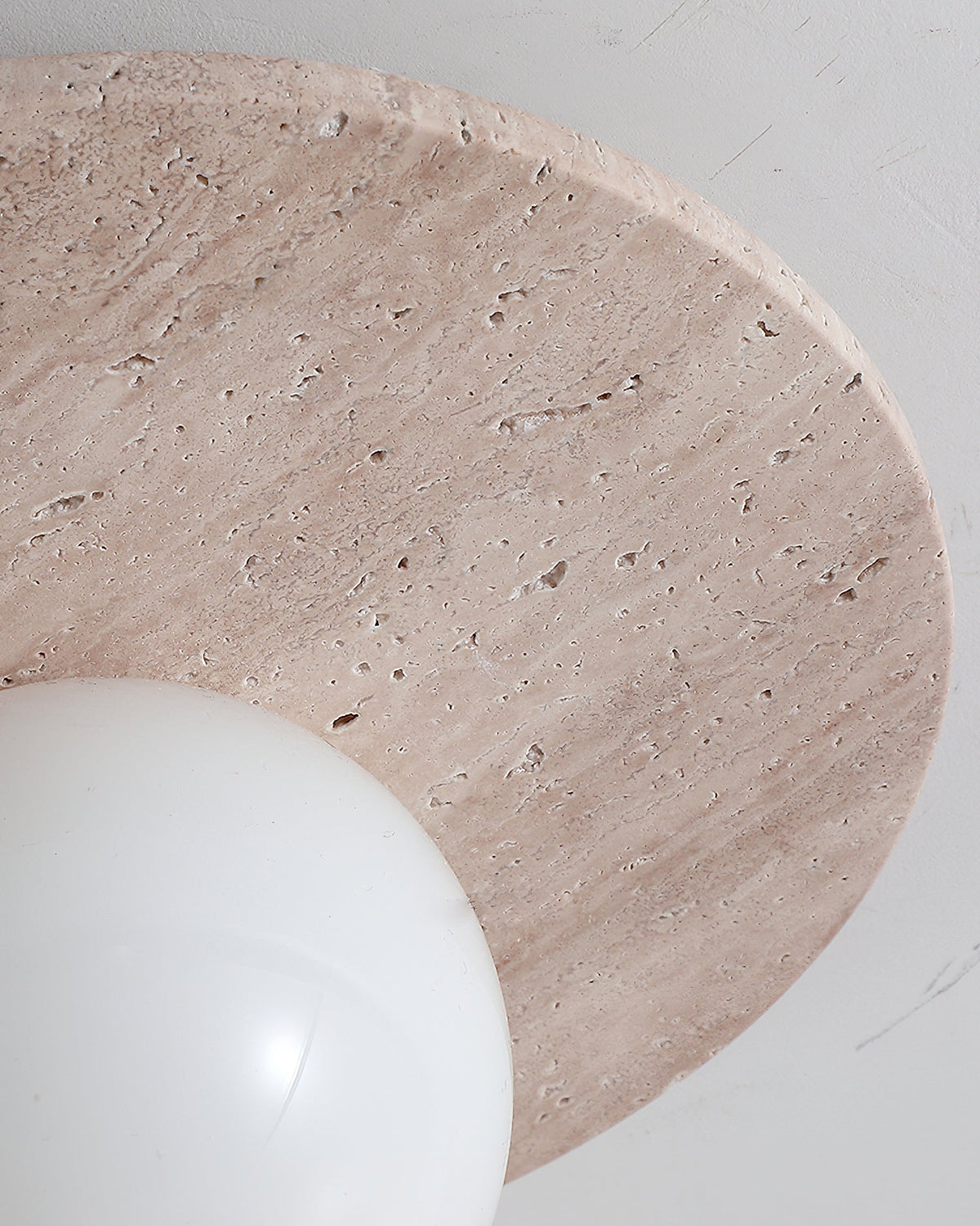 The beige and white finishes of the Elira Travertine Wall Lamp.