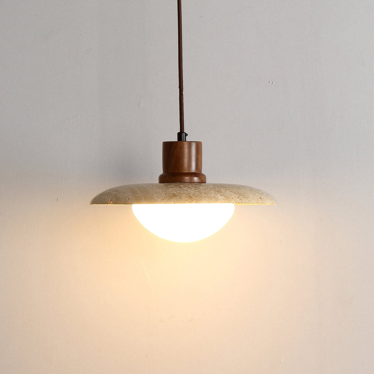 The Jadssox travertine pendant lamp hanging in a modern living room setting.
