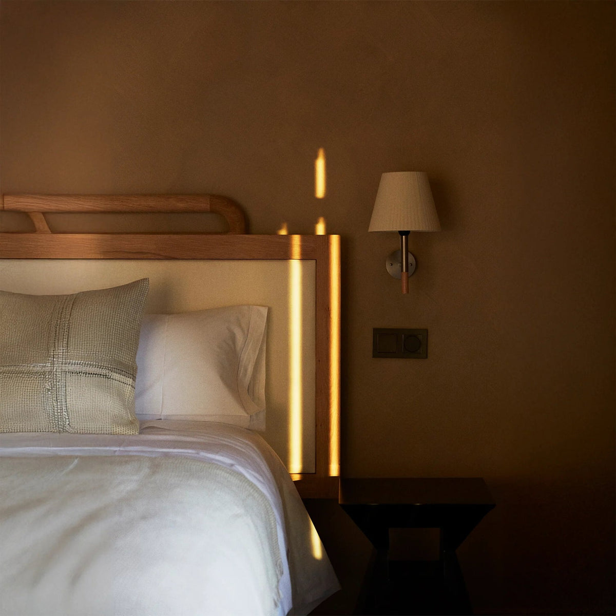 The Kilkee Wall Lamp shown in a modern bedroom setting.