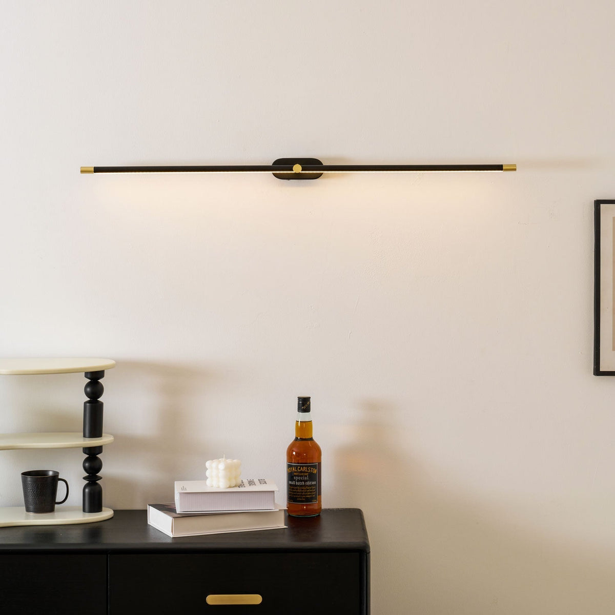 Lifestyle view of the black linear wall lamp in a bedroom.