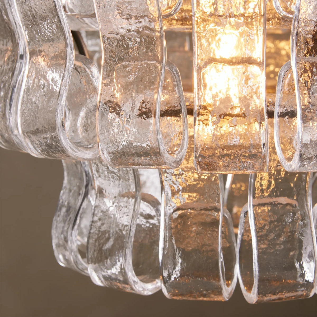 The Smoky Gray version of the Nirsa Pendant Light turned on in a dimly lit room.