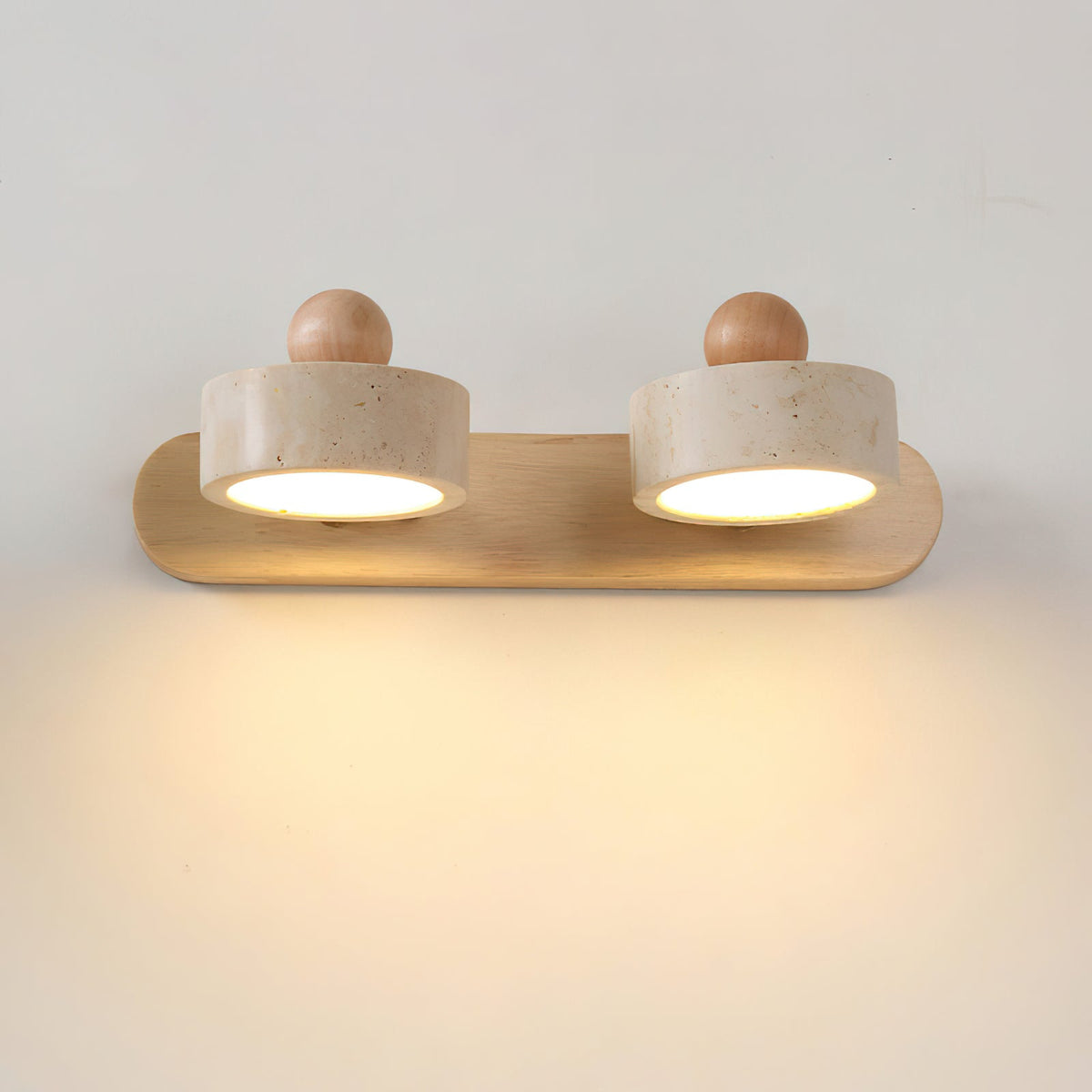 Piero Travertine Wall Lamp mounted above a bedside table, providing warm ambient light.
