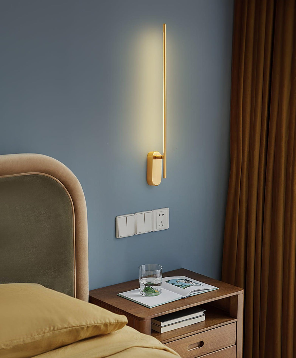 The brass sconce mounted vertically on a light-colored wall.