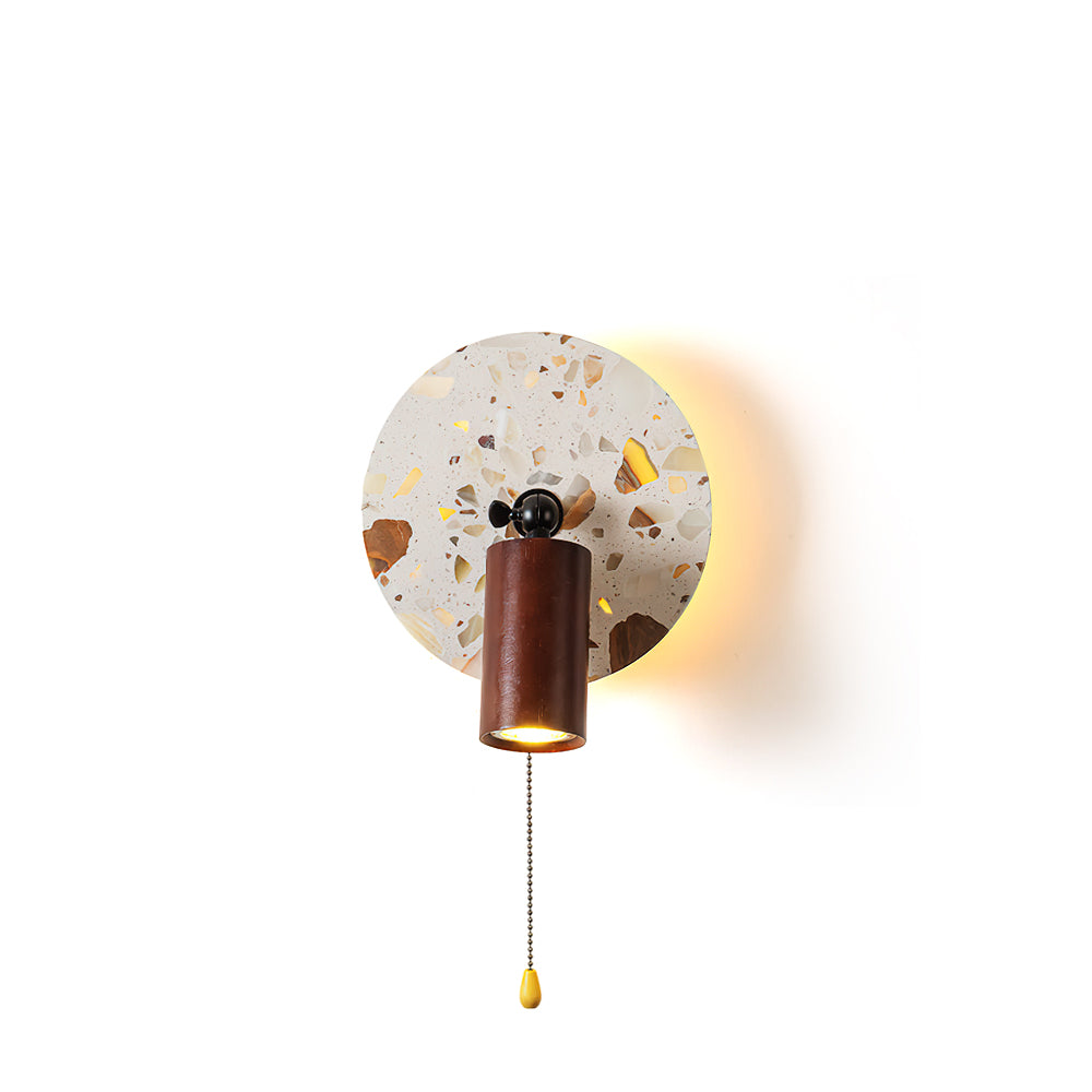Swizzle Wall Lamp with terrazzo-style stone backplate, shown lit.