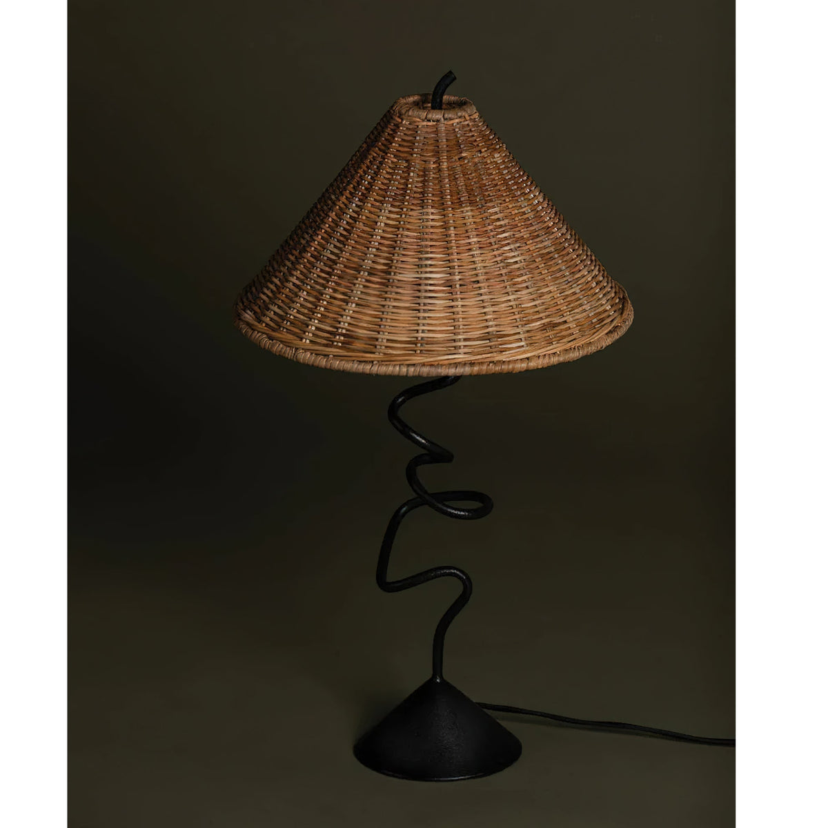 The Zigzag Table Lamp illuminating a cozy living room corner, casting a warm glow.