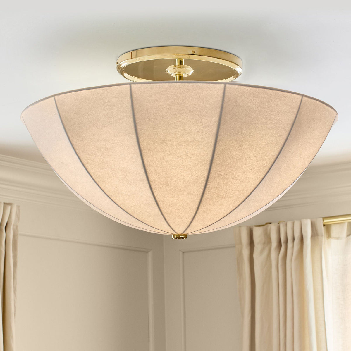 Close-up view of the white fabric shade and gold metal details of the Auden semi-flush mount.