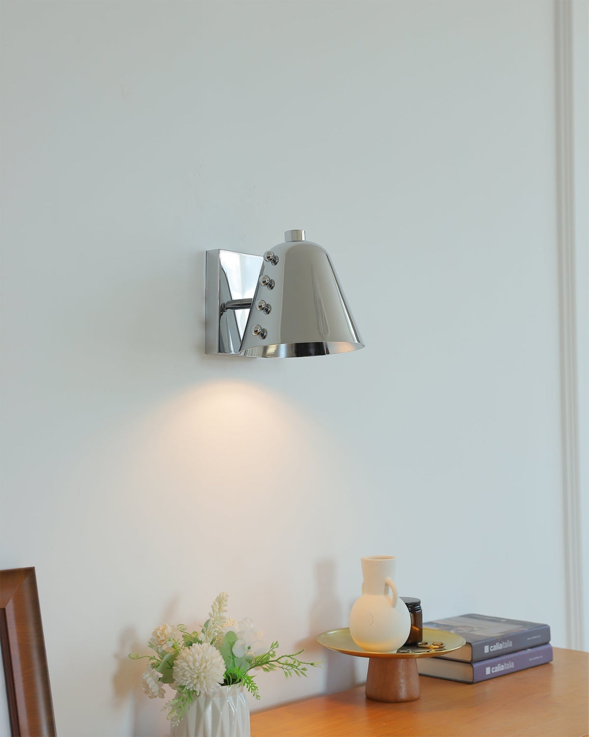 Bespoke geometric wall lamp in chrome finish in a minimalist room.