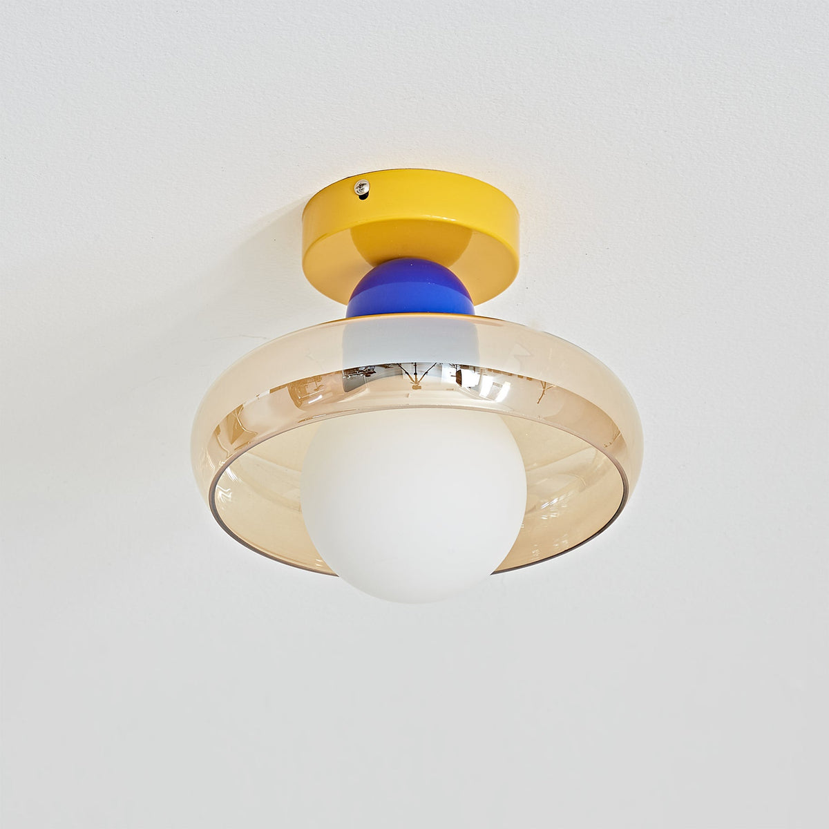 The Alabax Ceiling Light in blue, installed in a modern bedroom.