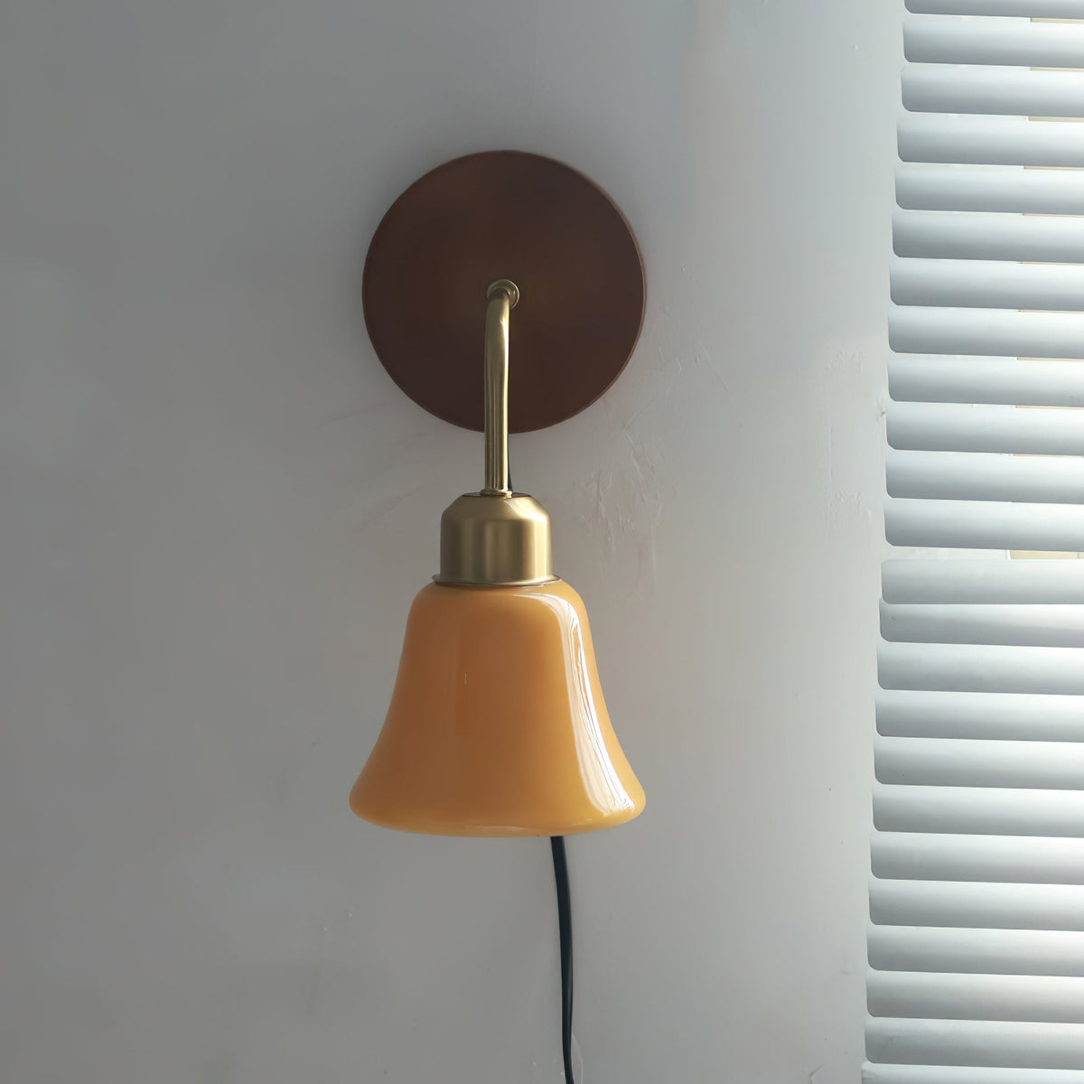 Daphne wall sconce shown installed on a wall, highlighting its plug-in cord.