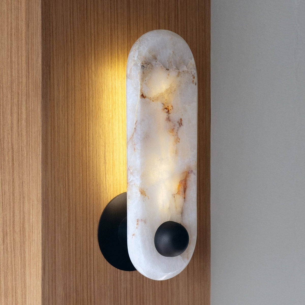 The wall sconce illuminated, showcasing the warm glow through the translucent alabaster.