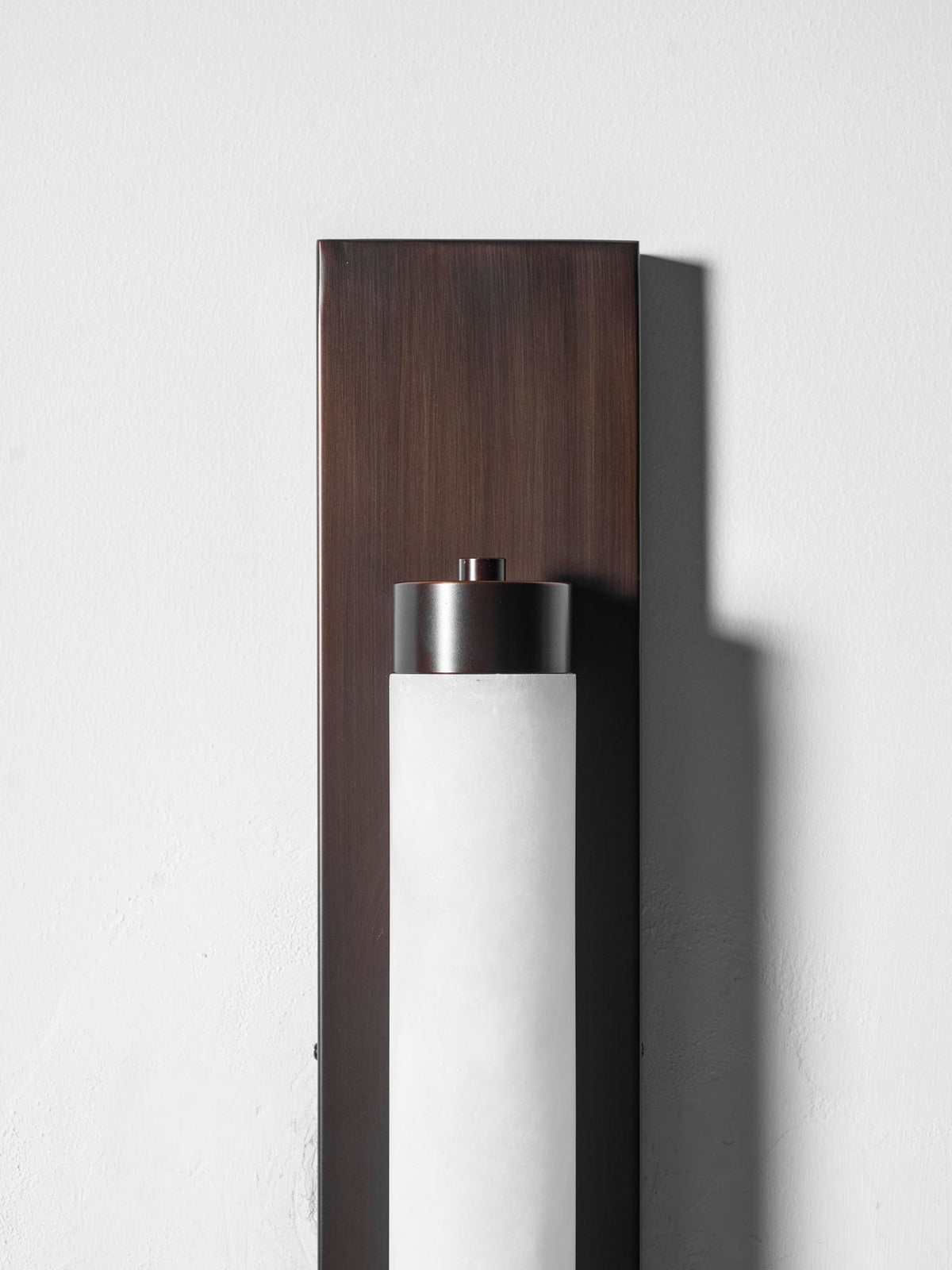 The bronze backplate of the Columnar Alabaster Wall Lamp.