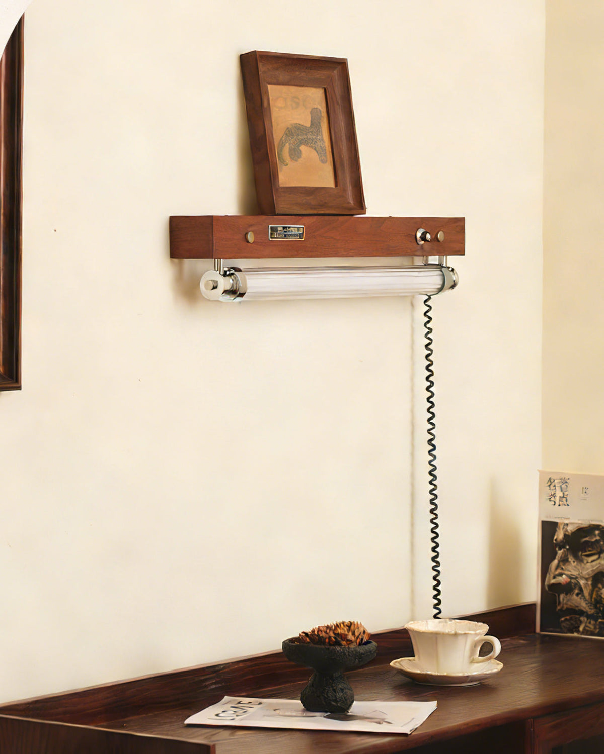 A lifestyle shot of the Hopper Wall Sconce illuminating books on a shelf.