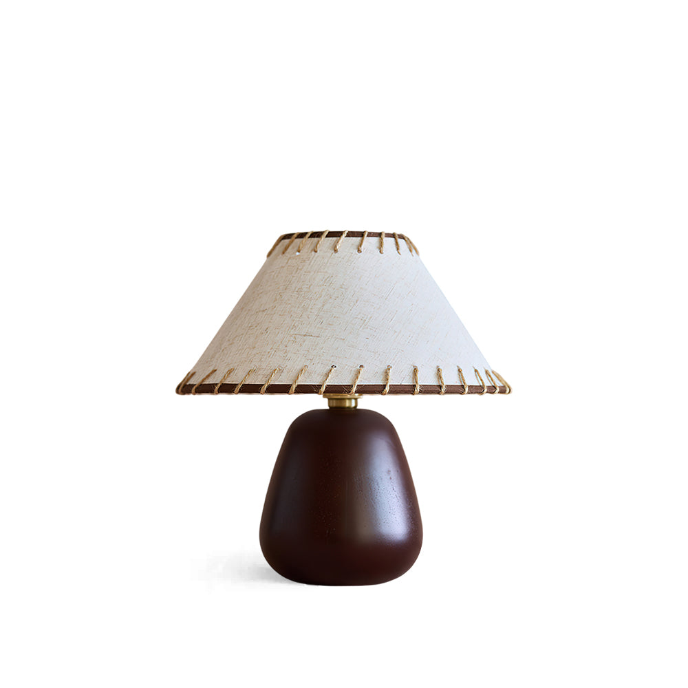 Douglas Walnut Table Lamp with a beige linen shade on a side table.