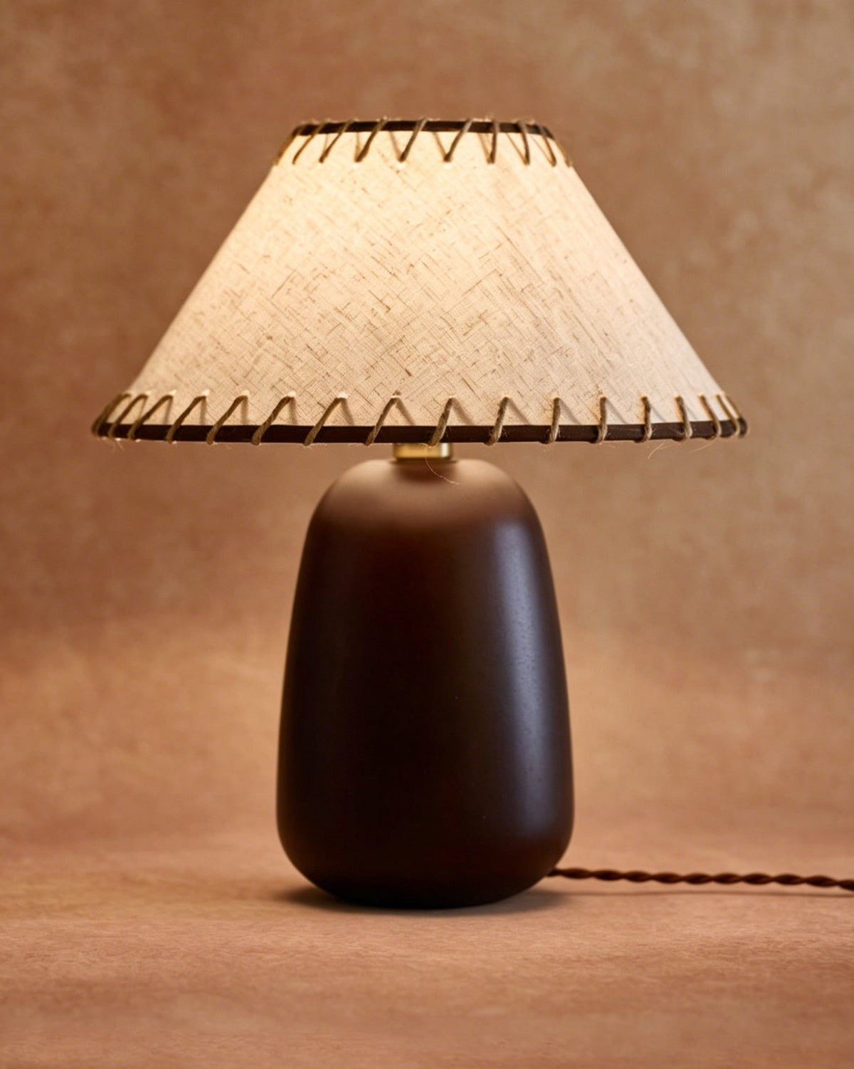 The lamp turned on, highlighting the texture of the linen shade.