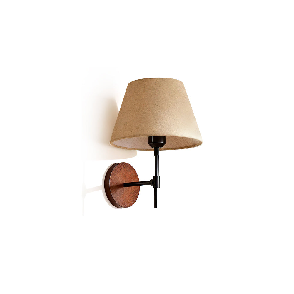 Dodie Wall Light with a beige fabric shade and walnut wood arm against a neutral wall.
