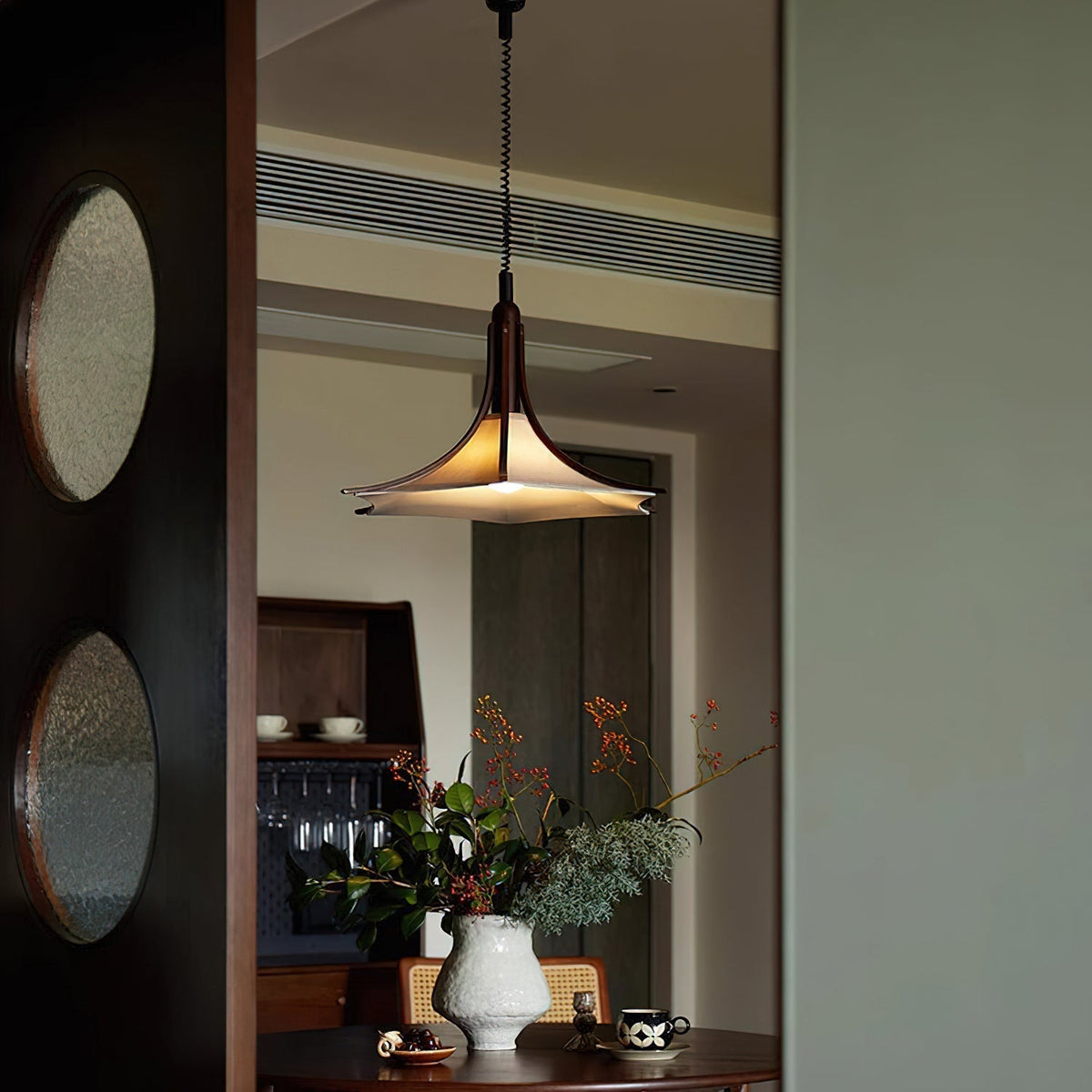 Close-up of the fabric diffuser and curved wooden structure of the pendant light.