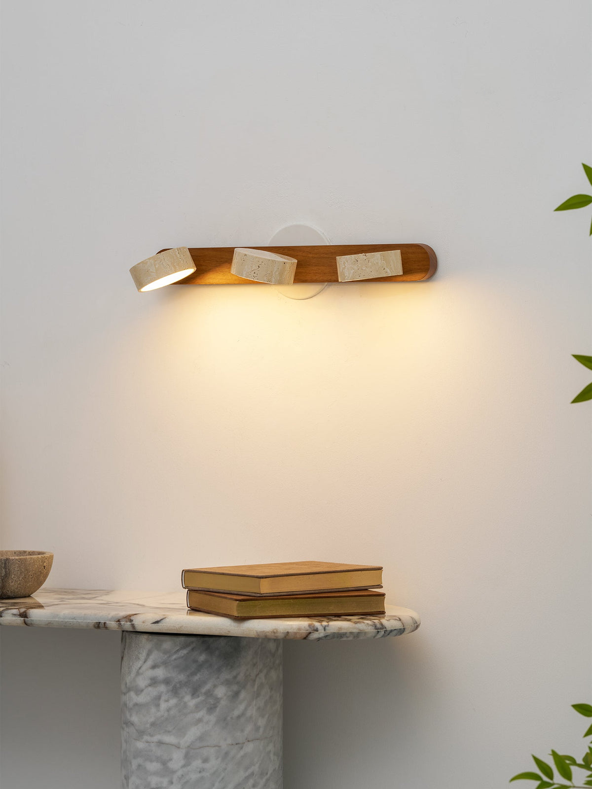Elias Travertine Wall Lamp shown against a dark colored wall for contrast.