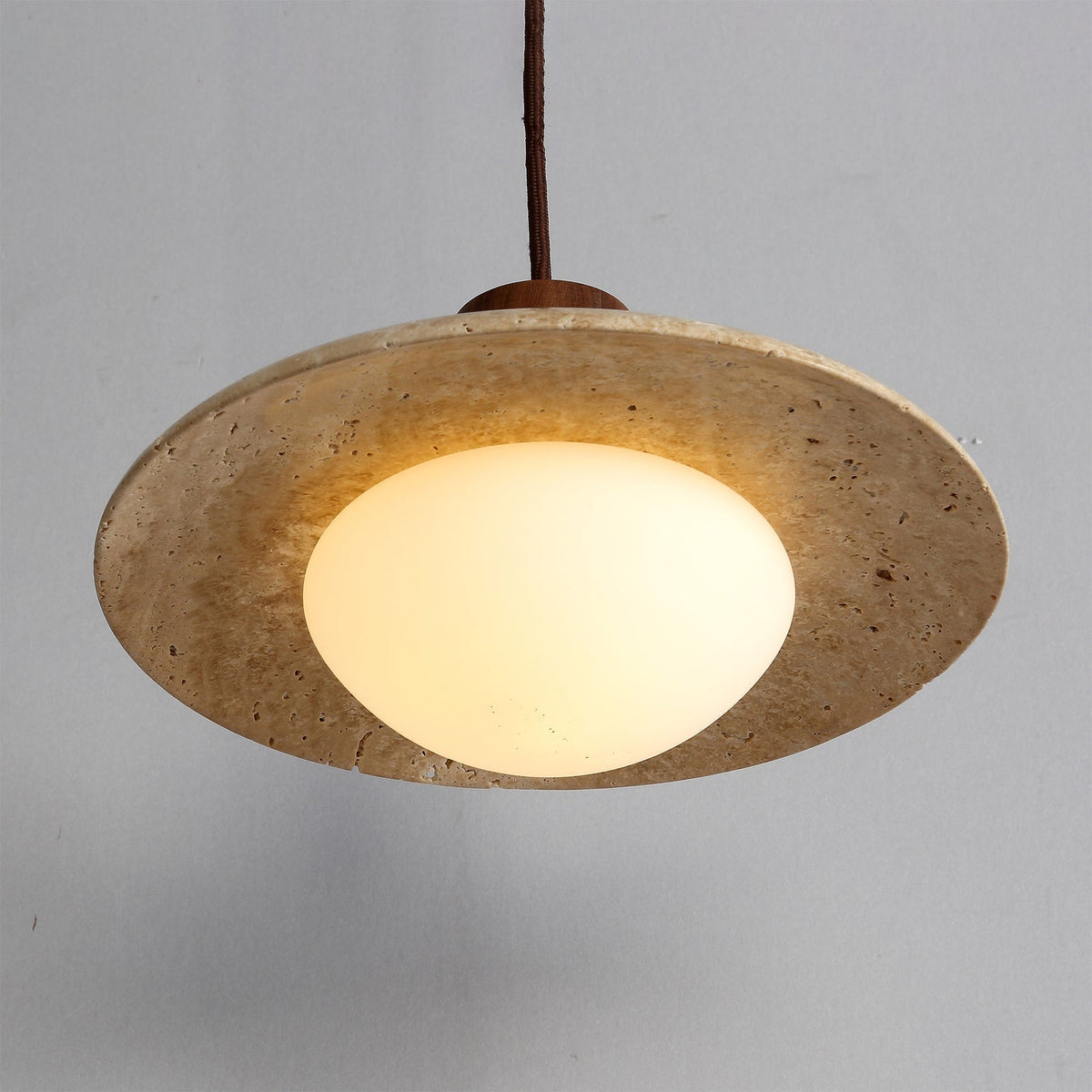A lifestyle shot of the travertine pendant lamp illuminating a corner of a room.