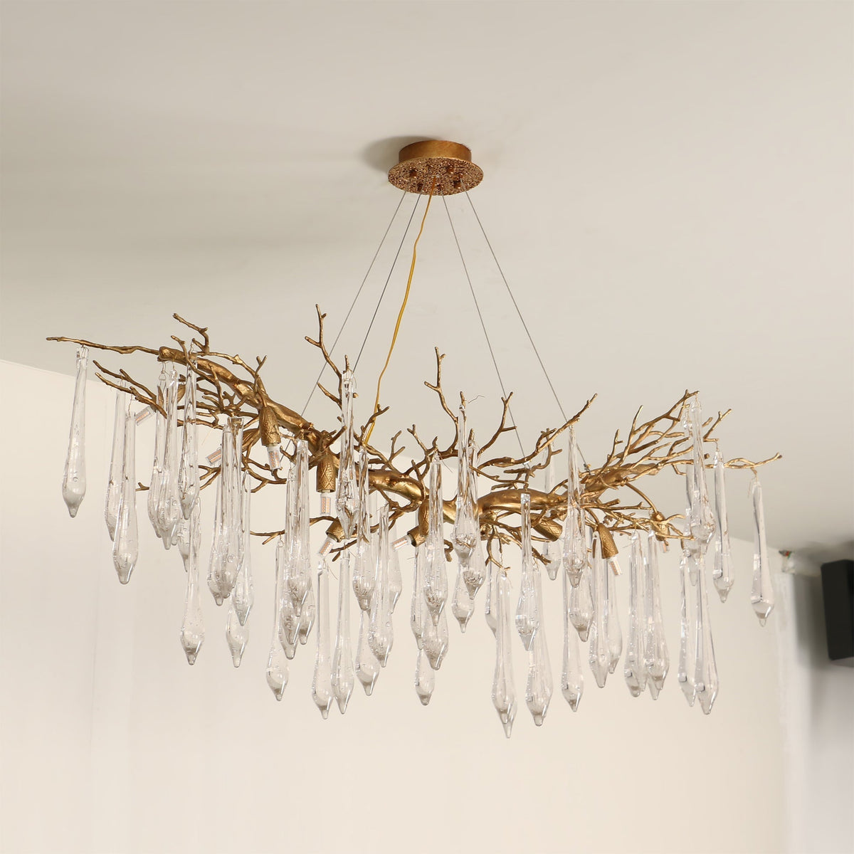 The organic, branch-like structure of the Janae Chandelier against a plain wall.