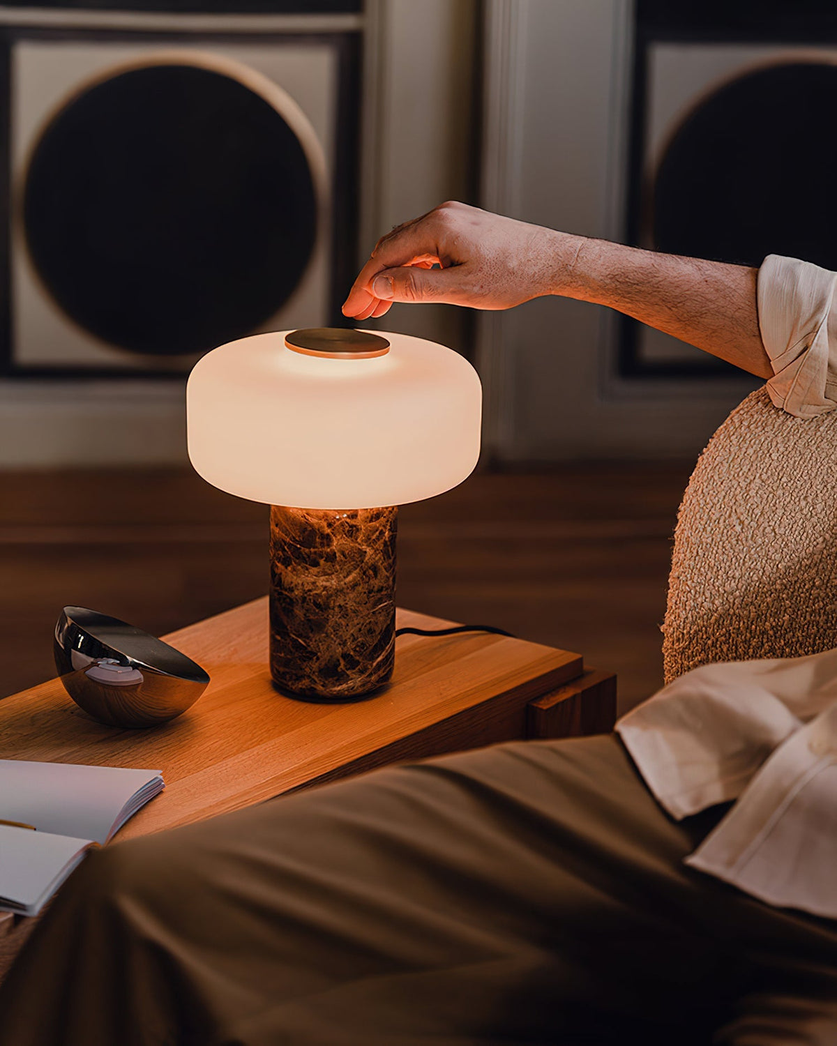 The Lennox lamp placed on a wooden side table in a modern living room setting.