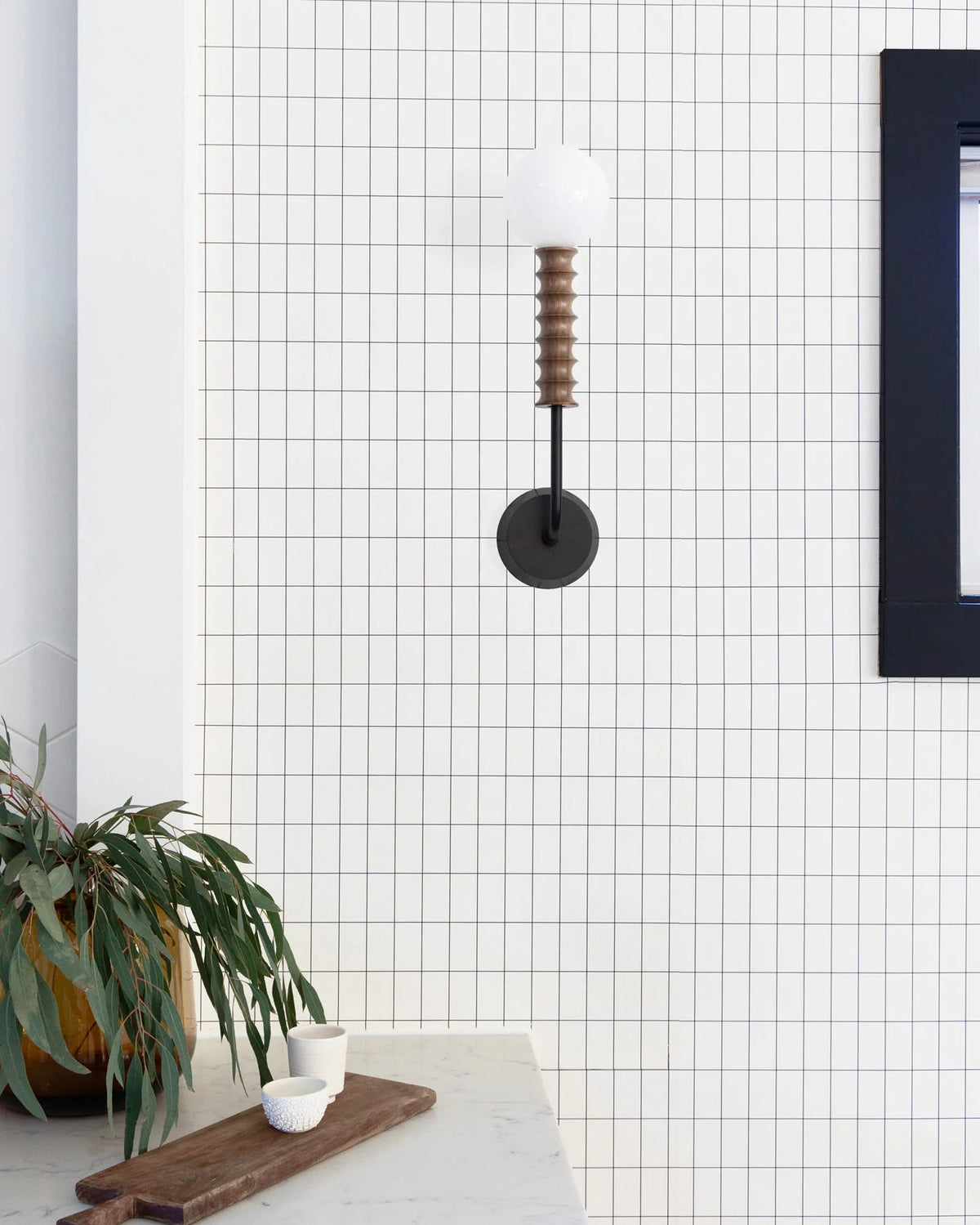Mobo Wall Lamp shown illuminated against a dark wall.
