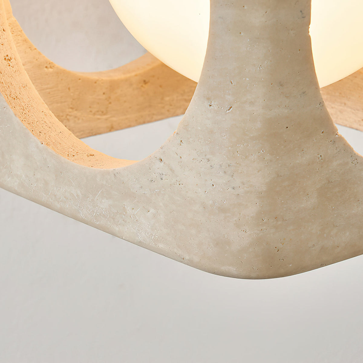 The beige travertine finish of the pendant light shade.