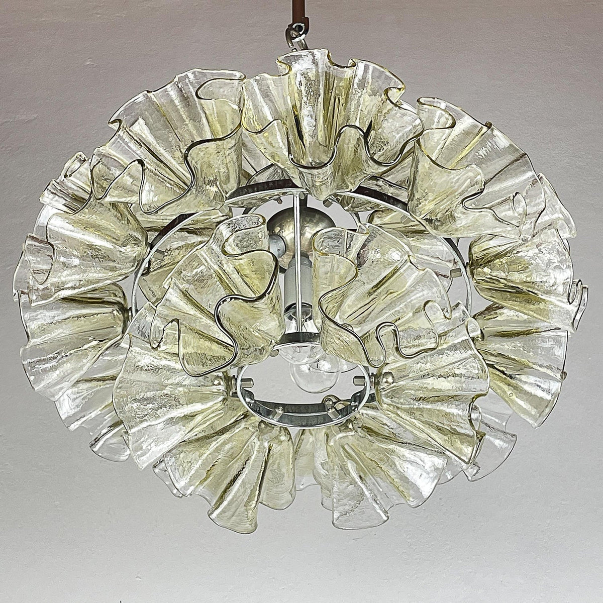 The chandelier illuminated in a dark room, casting a warm glow.