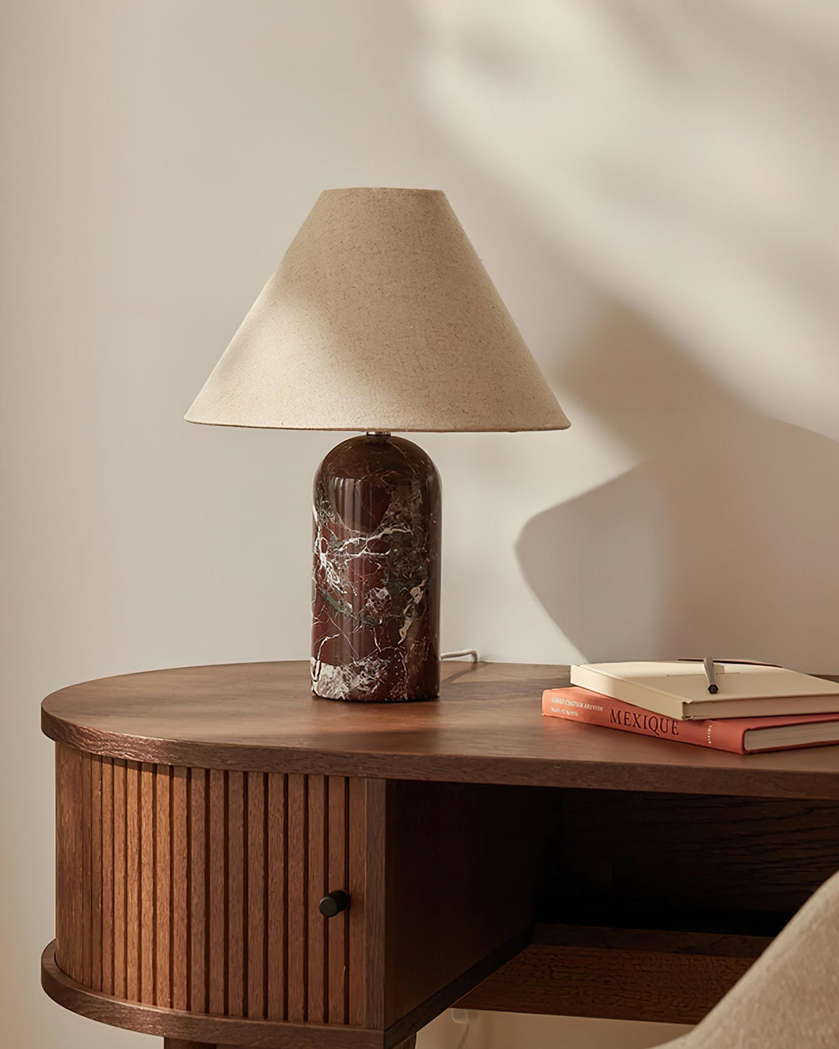 The Sacha table lamp placed on a wooden side table in a modern living room.