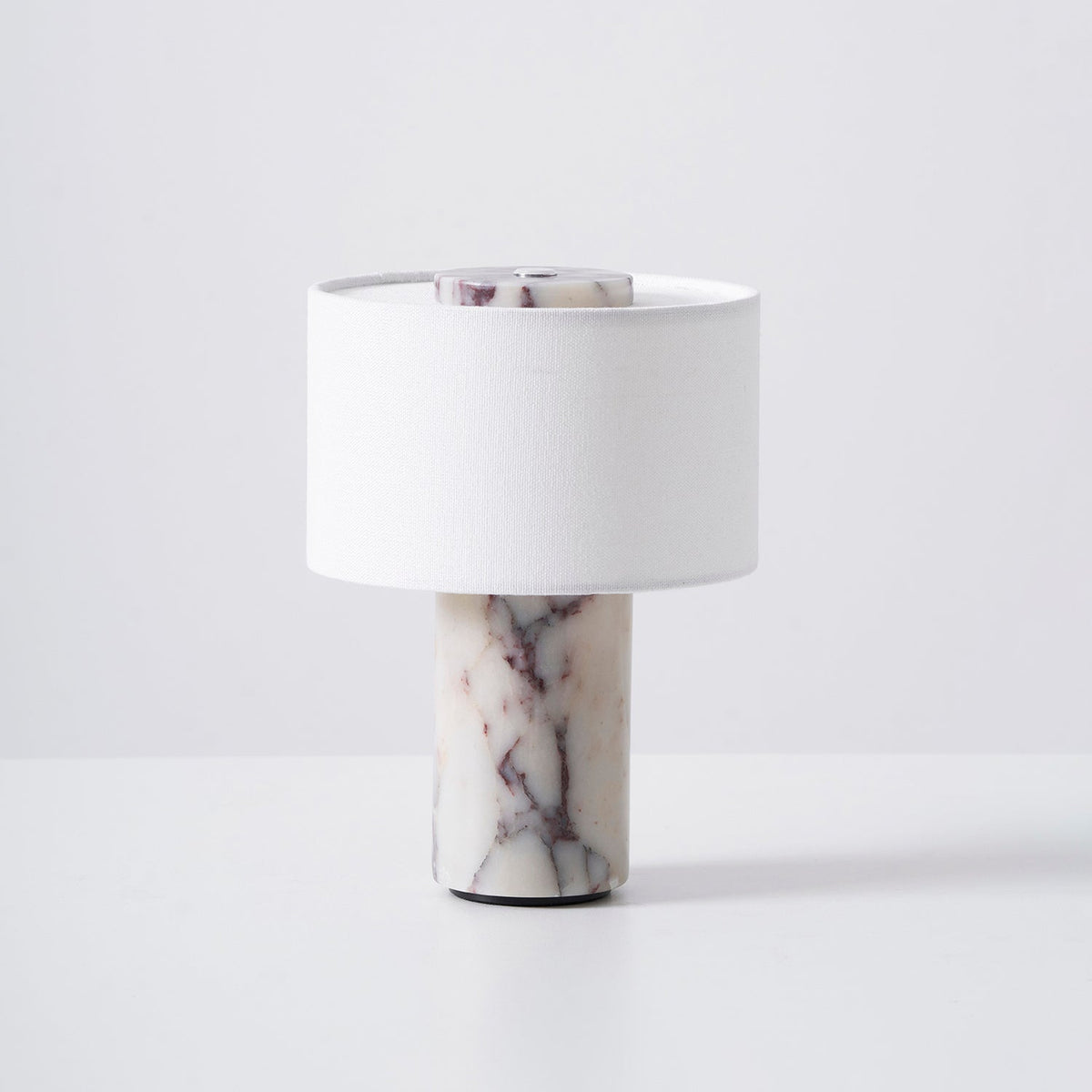 The Sediment Table Lamp on a bedside table next to a book.