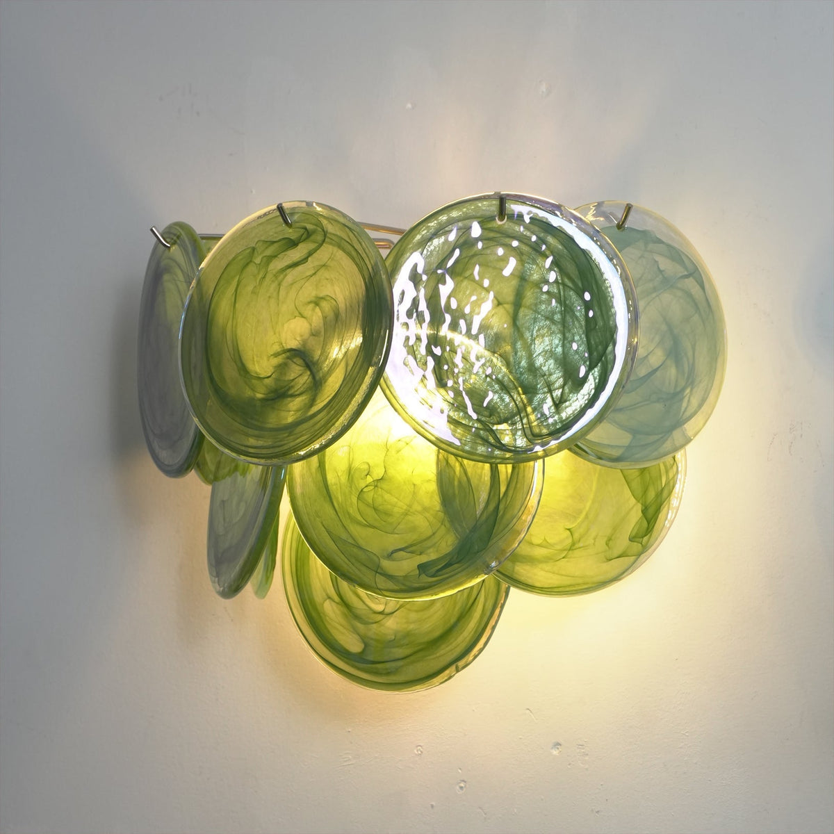 The white glass Vistosi Disc Wall Lamp against a dark wall.