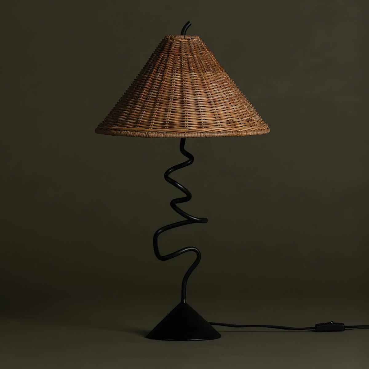 Detail shot of the sculptural zigzag-shaped black metal base of the table lamp.